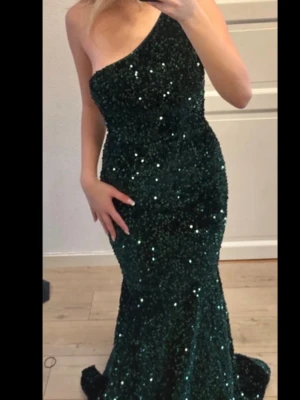 Mörkgrön balklänning med släp och paljetter - OBS pris kan diskuteras vid snabb affär! Jättesnygg lång klänning perfekt för bal eller gala. Jag är 166 och bär alltid storlek S❤️Köpt begagnad i mycket bra skick. Nypris runt 900kr. Märke: faeresty. Ett litet släp, skönt material❤️