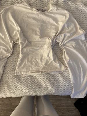 Vit långärmad topp i bomull - En enkel och stilren vit långärmad topp i mjuk bomull. Modellen har rund halsringning och normal passform, perfekt att matcha med jeans eller kjol. Passar dig som gillar basic-plagg med clean look.