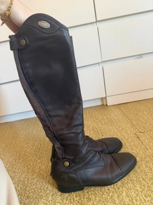 Parlanti passion 39 - Välanvända mörkbruna parlantistövlar i 39 MH (se storlekstabell sista bilden) något uttöjda så skulle säga att vaden passar 34 cm. Supersköna och följsamma stövlar som har mycket kvar att ge! Dragkedjor funkar super det enda som är bytt är snörningen i fram, den bytte jag till ej elastisk snörning för flera år sedan så det ska hålla! Köpta för flera år sen för ca 5000.