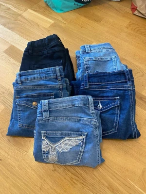 Klädpaket 160-170 - Säljer ett gäng jeans i olika blå nyanser, från ljusblått till mörkblått och svart. Några har snygga detaljer som broderade bakfickor och kontrastsömmar. Perfekta för dig som vill ha variation i garderoben. Märken och material varierar mellan paren. Storlek 160-170