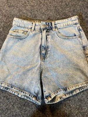 Ljusblå jeansshorts från Perfect Jeans - Säljer ett par klassiska ljusblå jeansshorts från Gina tricot. De har fem fickor, bälteshällor och stängs med knapp och dragkedja. Perfekta till sommaren och har en avslappnad passform med hög midja.