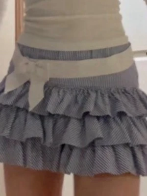 Polo Ralph lauren volangkjol med rosett - Söt kortkjol med blåvita ränder och flera volanger. Kjolen har en bred vit midjeresår och en stor rosett framtill för extra detalj. Perfekt för dig som gillar en lekfull och trendig stil.