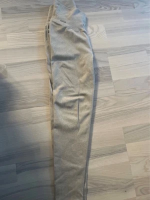Beige ribbade leggings - Säljer ett par beige ribbade leggings med hög midja och figurnära passform. Materialet är mjukt och stretchigt, perfekt för en avslappnad och snygg look. Passar dig som gillar stilrena och bekväma plagg. Obs -Metall-loggan har lossnat och är därför fastsydd igen med en något mörkare tråd. I övrigt är den i jättebra skick.