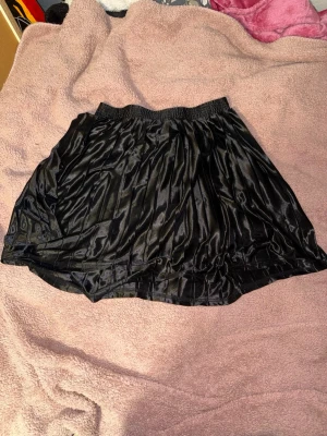 Sidenkjol - En svart sidenkjol med resårband i midjan. Den är knälång skulle jag säga