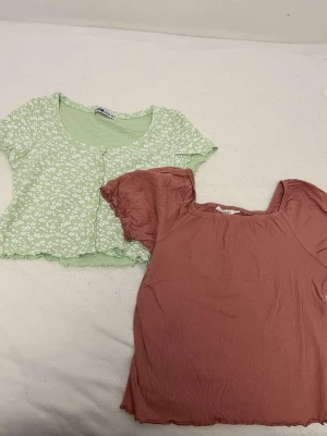 Grön blommig croppad topp med knappar - Söt ljusgrön croppad topp från Faded Glory med vita små blommor och knappar framtill. Toppen har korta ärmar och vågig kant nedtill, perfekt för en somrig look. Materialet känns mjukt och lätt.