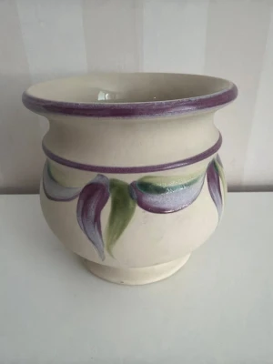 Handmålad kruka med lila kant Gabriel  - Säljer en handmålad kruka i keramik med lila kant och blommönster i lila, grönt och blått från Gefle keramik. Krukan har rundad form och bred öppning, perfekt för växter eller dekoration. Passar snyggt i fönstret eller på hyllan.