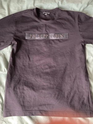 Philipp Plein tröja - Snygg svart långärmad tröja från Philipp Plein med ett tydligt logotyp-tryck på bröstet. Tröjan har rund halsringning och är gjord i mjukt bomullsmaterial. Perfekt för dig som gillar streetwear och vill ha något stilrent med exklusiv känsla.