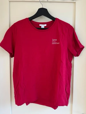 Röd t-shirt med tryck från Amisu - Fin röd t-shirt från Amisu, köpt på New Yorker, med diskret vitt texttryck på bröstet. Tröjan är i väldigt bra skick och har bara använts ett fåtal gånger. 