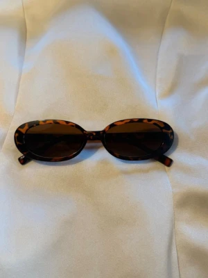  solglasögon i leopardmönster - Snygga ovala solglasögon med leopardmönstrad båge och mörka linser. Perfekt accessoar för dig som vill sticka ut och addera lite edge till din stil. Klassisk retroform som passar till många looks.