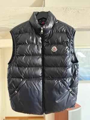 Moncler väst - Pris går att diskutera! Kvitto finns! Snygg dunväst från Moncler med glansig finish och klassisk logga på bröstet. Storlek 2 motsvarande S/M. Köpt för 7799kr mars 2024 på room 1006 Emporia Malmö. Endast använd fåtal gånger! Västen är mörkblå!