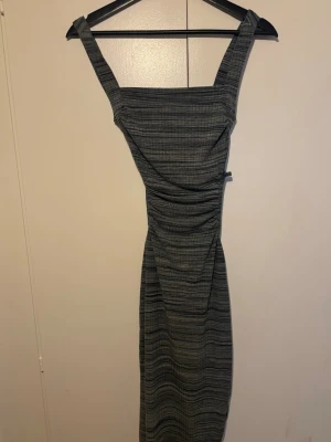 Fin Klänning  - Midiklänning som sitter snyggt mot kroppen, med öppen rygg och knytband.