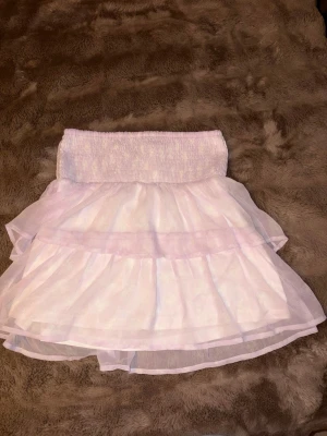 Vit volangkjol med resårmidja - Söt vit kjol med flera lager av tunn tyll och bred resår i midjan. Kjolen har volanger som ger en fluffig och lekfull look. Perfekt för dig som gillar en romantisk och trendig stil. Den e från Vero Moda 