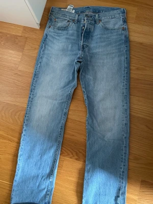 Levi's ljusblå raka jeans - Klassiska ljusblå jeans från Levi's med rak passform och fem fickor. Jeansen har en tidlös look med knappgylf och är tillverkade i slitstark denim. Perfekta för en avslappnad och trendig stil. Stolek 33/34. Använda ett par gånger men inget som märks på.