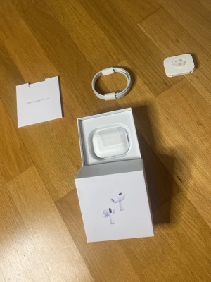 Apple AirPods Pro 2nd generation trådlösa hörlurar - Säljer ett par Apple AirPods Pro med laddningsetui, laddkabel och extra öronproppar. Hörlurarna är vita och har en stilren, kompakt design i plast. Perfekta för dig som vill ha grymt ljud och smidig anslutning till din iPhone eller andra Apple-enheter.