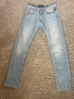 Ljusblå jeans från Replay - Säljer ett par snygga ljusblå jeans från Replay med klassisk femficksmodell och raka ben. Jeansen har snygga slitningar och tvättade detaljer för en avslappnad look. De har  dragkedjegylf och Replay-logga på linningen. Modellen ROB och storlek 30/32💕 Pris kan diskuteras 