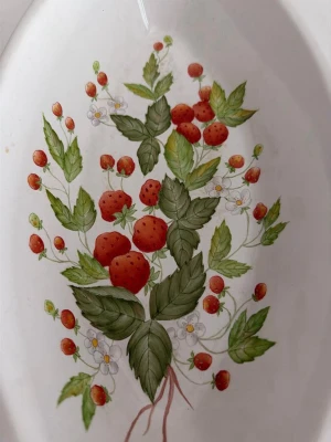 Handmålad porslinsform med jordgubbsmönster av Birthe Christensen - En handmålad porslinsform med ett detaljerat jordgubbsmönster. Formen är signerad av Birthe Christensen.Längd 32 cm, bred 17 cm, höjd 6 cm.