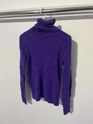 Lila polotröja från lauren Ralph Lauren - Säljer en ribbstickad lila polotröja från Lauren Ralph Lauren . Tröjan har lång ärm, hög polokrage och är gjord i ett mjukt, stretchigt material som sitter snyggt på kroppen. Perfekt för dig som vill ha en färgstark och trendig look. Etiketten har gått av!