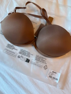 Push up BH från Skims - Säljer en helt ny push up bh från SKIMS.  Modell: Ultimate Strapless Push-up bra Storlek: 30D (65D) Färg: SIENNA  • Amerikansk bh-band i storlek 30 motsvarar europeisk 65  🌸 PS: Jag säljer även en bh i en annan modell i både Sienna och Onyx, samt andra plagg från SKIMS 🌸