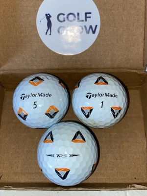 TaylorMade TP5 Pix 3-pack  - Tre vita golfbollar från TaylorMade med svart och orange geometriskt mönster. Två av bollarna är märkta med siffrorna 1 och 5, och en har TP5-logga. Perfekta för golfträning eller tävling.