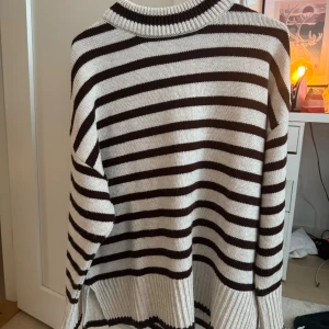 Randig stickad tröja Sisters Point - Snygg stickad tröja från Sisters Point i storlek M. Tröjan har breda horisontella ränder i brunt och vitt, rundad halsringning och avslappnad passform. Perfekt för lager på lager och ger en trendig look till din outfit.