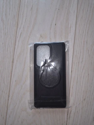 Svart mobilskal med hållare - Snyggt svart mobilskal för S25 Ultra med inbyggd hållare på baksidan. Vet ej var den är ifrån då min kille fick den i present men det var tydligen fel modell så den är i nyskick men vet ej var kvittot är 