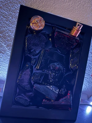 Versace Eros Flame parfymflaska - Säljer en Versace Eros Flame parfymflaska i röd glasdesign med guldfärgad spraykork. Flaskan har en elegant och lyxig look med tydliga Versace-detaljer. Perfekt för dig som gillar exklusiva dofter och snygg design på parfymhyllan.