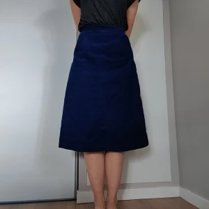 Manchester kjol - Kjolen är i en marinblå färg och manchester tyg, hög i midjan och har två fickor fram. Dragkedja baktill. Går ned till vaderna på mig som är 166,5cm lång. Storlek S-M, den är relativt smal runt midjan, skriv pm om du vill ha mått. Köpare står för frakt. 💙