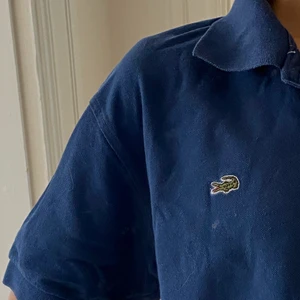 Lacoste pikétröja - Marinblå vintage pikétröja från Lacoste i väldigt bra skick! Storlek XXL men passar även bra oversized på mindre storlekar, som mig.