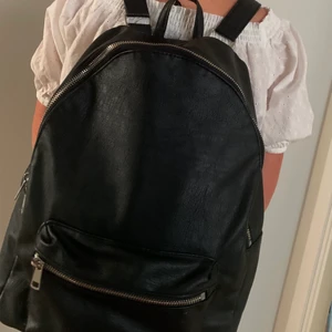 Svart ryggsäck  - Svart skin väska som är bra skick men använd mycket.