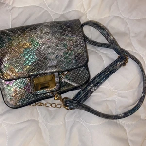 Axelbandsväska - Axelbandsväska i fina färger. Guldiga detaljer. Köpt på Primark.