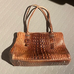 Handväska - Brun handväska i konstgjort krokodilskinn som köptes från humana secondhand. Väskan har plats för mycket, en dator till exempel. Den har tre stora fack och metallpiggar under så att materialet inte slits. 