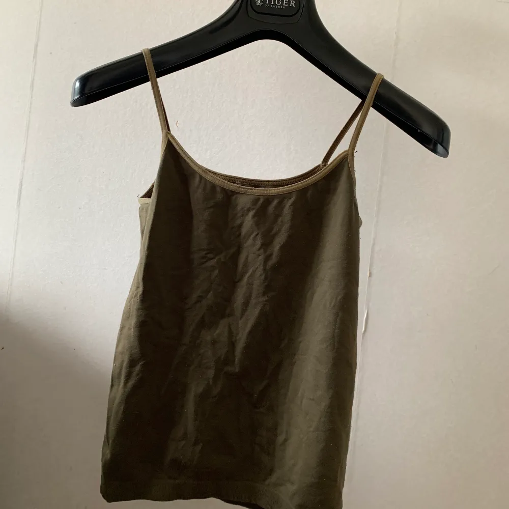 Ett enkelt linne i militärgrön färg i stretchigt material . Övrigt.