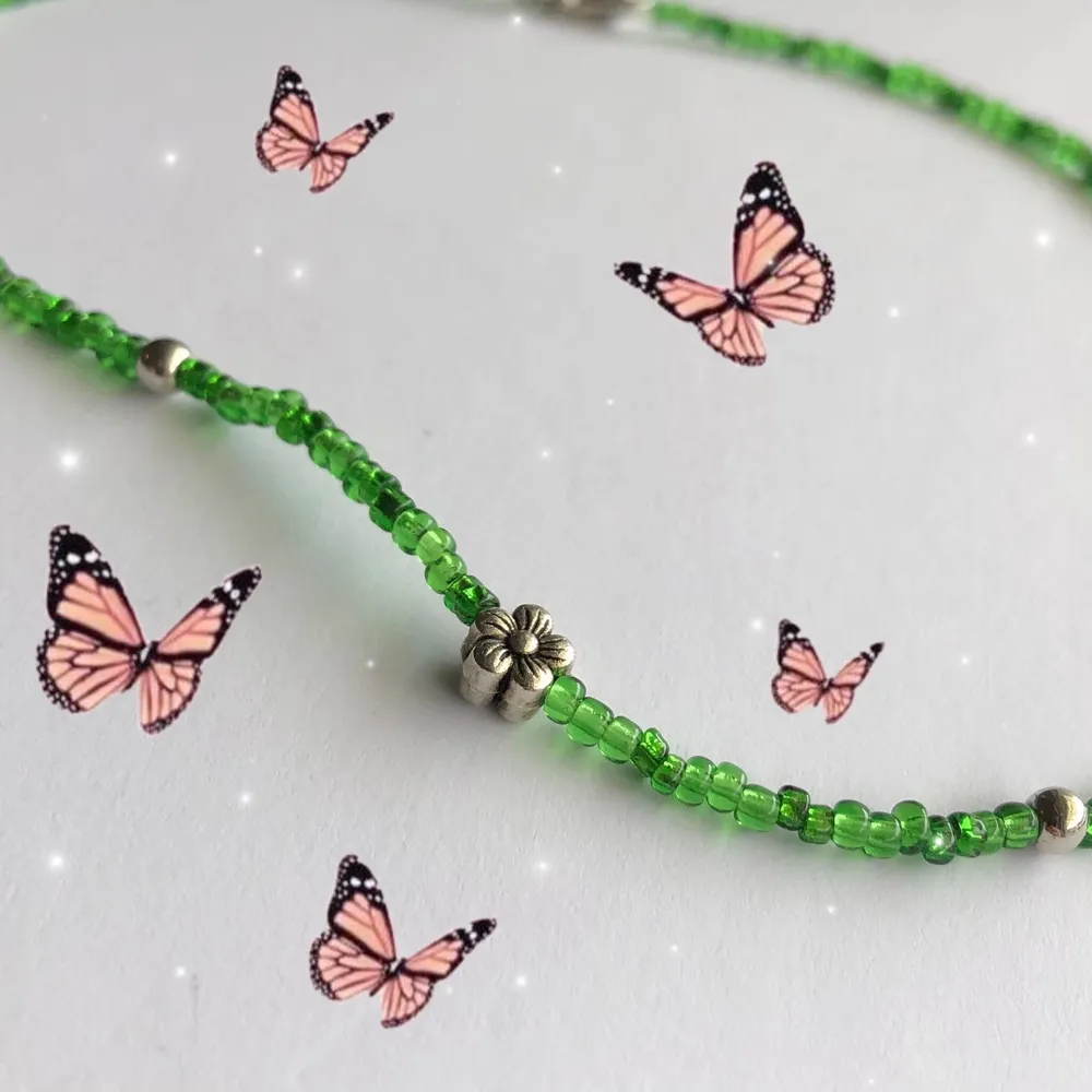 Halsband med seed beads i grönt & har en liten silvrig blomma🌸🌷Gjort med nylontråd och har en förlängning på 3 cm. Säljer för 40kr + 12kr i frakt!. Accessoarer.