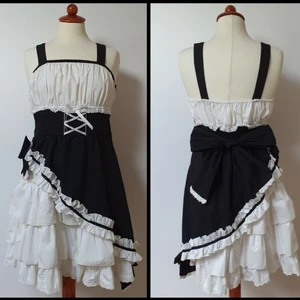 Lolita/kawaii klänning - Svart och vit klänning med knytbar rosett i ryggen och dragkedja på sidan. Den går ned till mina knän och jag är 160cm lång. Har använts fåtal gånger av mig. Den har 2 fläckar som är svåra att se. Den röda är smink men då klänningen har använts så lite så har jag inte försökt att tvätta bort. Axelbanden är justerbara med knappar.