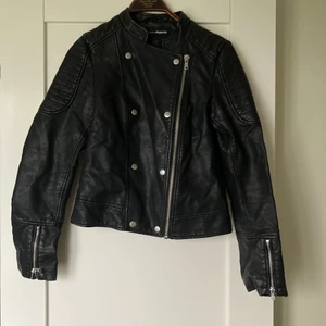 Skinnjacka (ej äkta skinn) - Skinnjacka från Kappahl (ej äkta skinn) i storlek S (passar även M). Finns lite åldersslitage på insidan av jackan (se bild). 