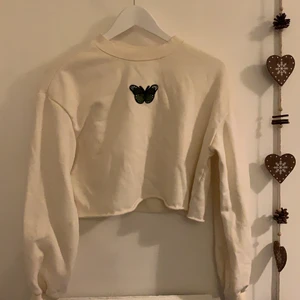 Croptop med fjäril - Beige croptop med en grön fjäril. Broderiet har jag fäst själv men tröjan är från HM. Offwhite/beige färg (ej vit)