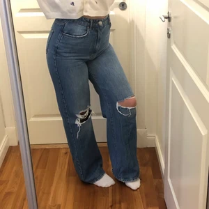 Jeans - Ett par mörkblåa jeans med knä-slitning. De går ut lite mer där nere men inte bootcut. Ganska långa, själv är jag 173 cm lång. I bra skick. 