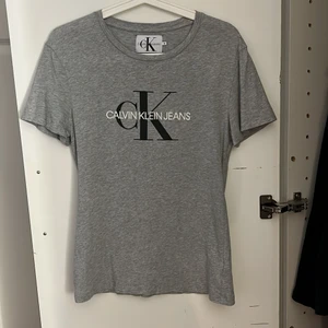 Calvin Klein T-shirt  - En grå T-shirt från Calvin Klein i storlek S, små hål vid lappen