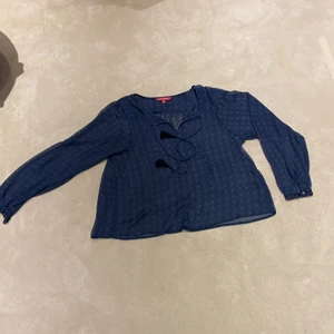 En blå blus som är genomskinlig. - En blå blus med fina detaljer. Syns igenom men dett passar jätte bra att ha ett svart linne under.