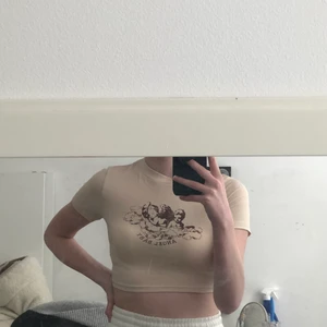 Shein strl M/38 - Beig croptop från shein med tryck. Oanvänd i helt nytt skick. Mjukt material, sitter tajt men är väldigt stretchig.                    Köpt för 50kr men säljer för 45kr (pris går att diskuteras)