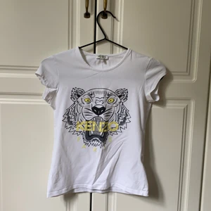 Kenzo tröja - Jag säljer nu min fina T-shirt från Kenzo, då den tyvärr blivit för liten. Trycket är i bra skick. Den är i storlek 14A, så runt en XS. Jag säljer den för 230, pris kan diskuteras genom att kontakta mig