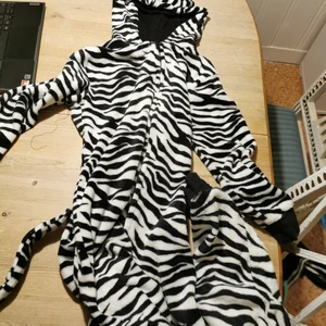Superfin Zebra onesie! !  - Superfin Zebra onesie i fint skick. Välanvänd men väldigt bra skick! Köptes för 279kr på lindex , mitt pris 155kr. Säljes nu pga för liten. Hat ett litet hål på knäet, men går att laga! 