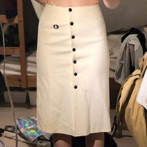 säljer en supersöt lång vit pencilskirt från frankrike! köpt i secondhandbutik och använd en gång. har superfina knappar med mönster på och en liten segelsymbol. i fint skick!