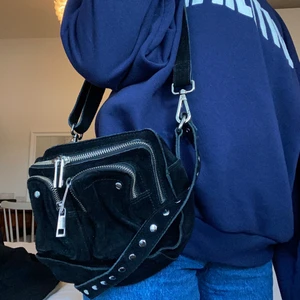 Nunoo ”ellie new suede” - Säljer min Nunoo ”ellie new suede” väska i svart mocka! Använd några gånger men fint skick bortsett från att mockan tyvärr blivit lite ”smulig”, se bilder!! Nypris är 1499kr men säljer därför för 300 inkl frakt! Har både kort band och ett långt som går att ta av, finns massor av fack för förvaring!