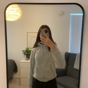 Polo Ralph Lauren grå hoodie - Hoodien är använd men fortfarande i bra skick. Hoodien är grå och har en mörkblå logga format som en polo spelare vid bröstet. Jag är 170 cm och hoodien har en lite kortare passform med långa ärmar. Hoodien har ett väldigt litet hål vid fikan därav dras priset ner. Nypris 900kr.