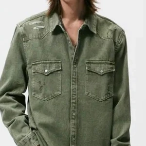 ZARA RIPPED DENIM OVERSHIRT Size M - Relaxed fit overshirt with lapel collar and long sleeves with buttoned cuffs. Patch pockets with flaps at chest. Ripped washed effect. Front button closure.