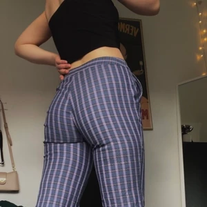 Lila-rutiga byxor - Ett par lila, trekvartslånga byxor med en low-/midwaist. Superfin passform och är en aning utsvängda längst ned vid anklarna. Materialet är tjockt och de har lite stretch i sig men inte supermycket. 95% Bomull 4% Polyamide och 1% Elastane. Har aldrig kommit till användning!