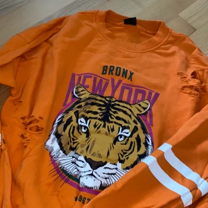 Tröja från Gina Tricot - Säljer denna orange tröja från Gina Tricot. Hålen på tröjan är orginal så det är ingenting som jag själv har gjort. I bra skick, inte alls använd mycket. Storlek XS men passar även en S✨