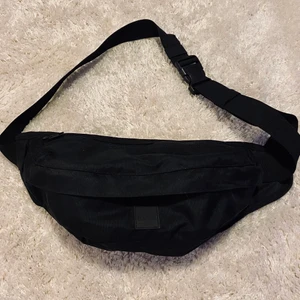 Stilren midjeväska 🖤 - Säljer den här snygga och smidiga midjeväskan från Urban Classics! 🖤 Den är använd cirka 2 gånger och är i jättebra skick! Spännet går att justera och väskan har en ficka inuti och en utanpå. Kontakta mig om du har frågor! Det går att frakta väskan billigare än det som är valt på annonsen för 66kr, men då är frakten inte spårbar 🤍