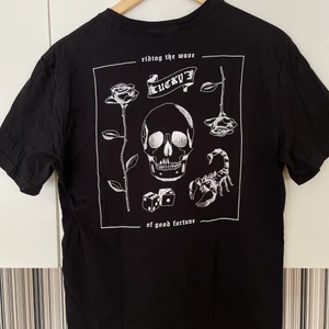 Svart t-shirt med vitt tryck - Jätte cool svart t-shirt med vitt tryck på baksidan och liten text på framsidan, där det står ”lucky”😛 Köpt på H&M och bara använd en gång så super skick, finns heller ej att köpa längre! Den är i storlek S, men skulle säga att den är lite oversized på S och sitter bra på M också☺️ Kontakta vid frågor, fler bilder eller om du vill köpa! Köparen står för frakten!